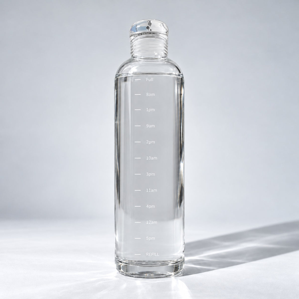 Nivosa Clear Bottle, 500 ml glass water bottle with white hourly time markers, on a light studio background